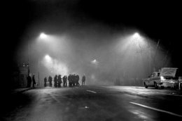 Tear gas, illuminated by street lights, fills the air as police wearing gas masks await possible further trouble in an African American area of northwest Washington on April 5, 1968. Crowds looted and started fires after learning of death of Dr. Martin Luther King Jr. (AP Photo/Charles W. Harrity)