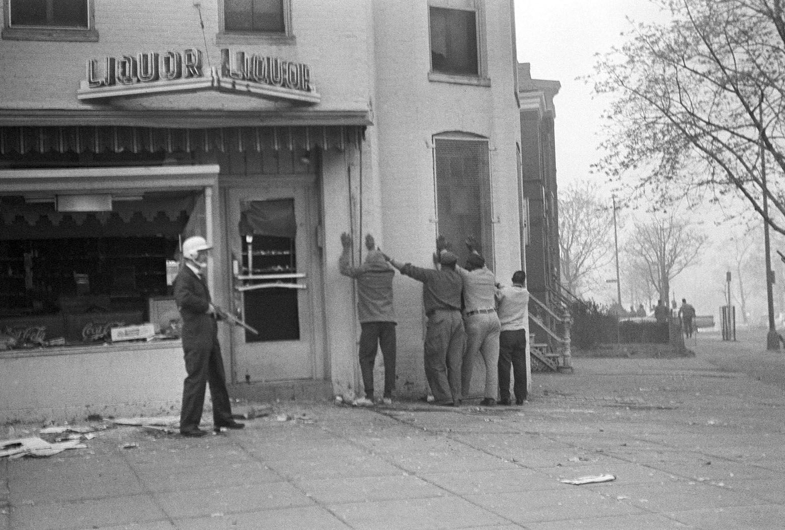 A helmeted policeman, armed with a shotgun, lines up four men after the window of a liquor store was smashed in northeast Washington on April 5, 1968 during renewed looting and burning. (AP Photo/Dozier Mobley)