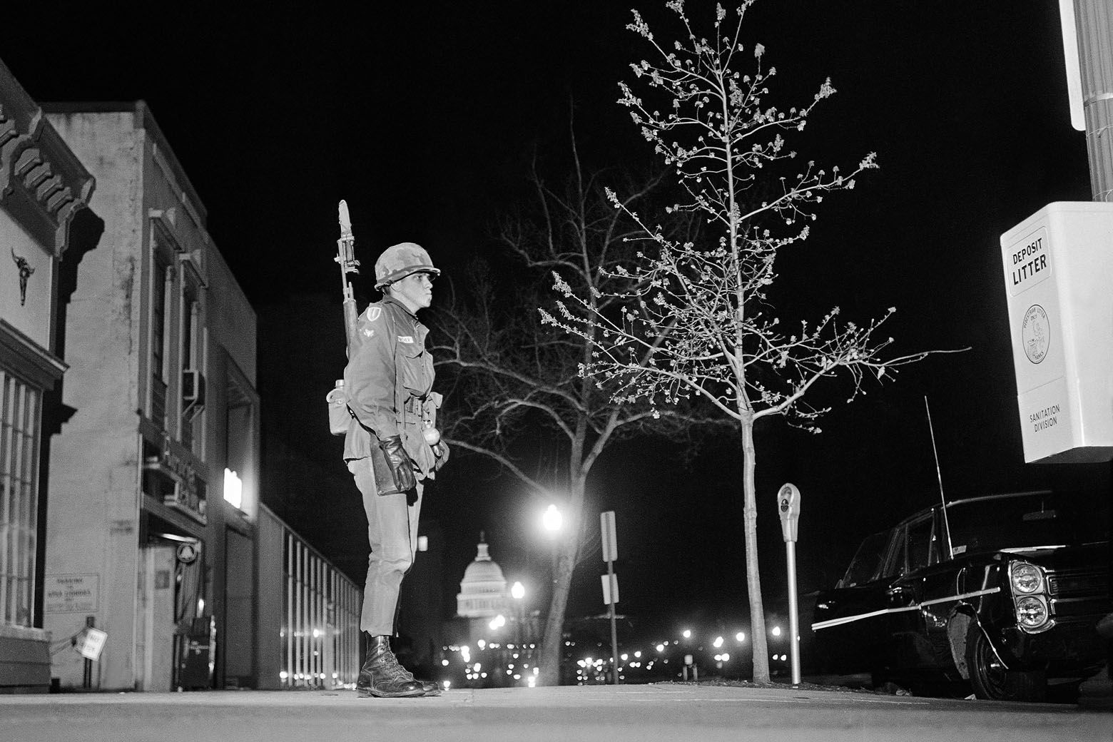 A soldier keeps watch as he stands guard along Pennsylvania Avenue near 7th Street, in the northwest section of Washington, April 6, 1968. The street is deserted, with a curfew imposed at 4 p.m., before darkness. The lighted dome of the U.S. capitol building is in the background. (AP Photo/Bob Schutz)