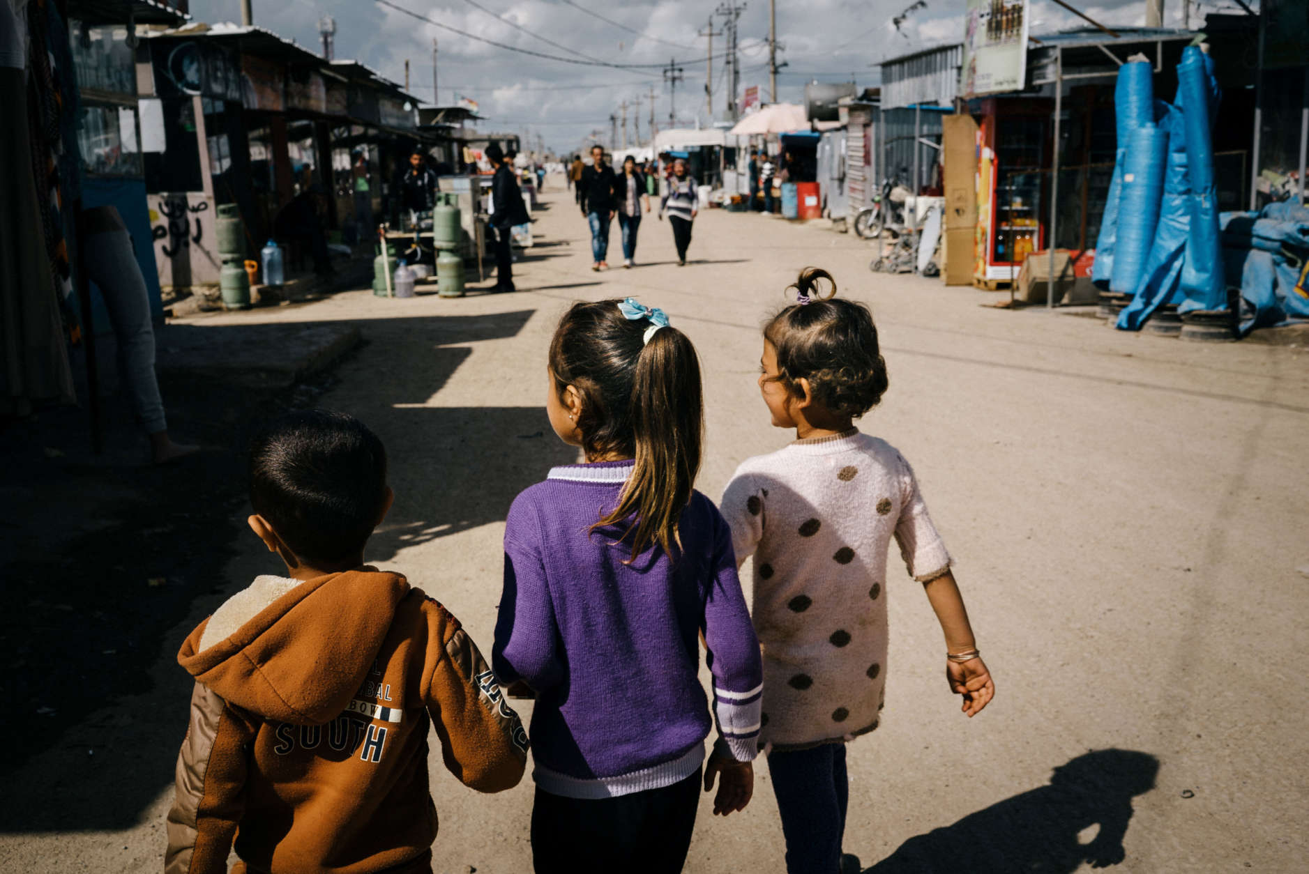 In this March 6, 2016 photo, Winda Farman Haji, right, a 5-year-old refugee from a town outside Malikiyah in northeast Syria, walks back to her tent after school alongside friends at Kawergosk refugee camp in Iraq where she has lived since 2012 . Winda shows great talent in drawing and her parents say she is very impatient to go to kindergarten every morning. (AP Photo/Alice Martins)