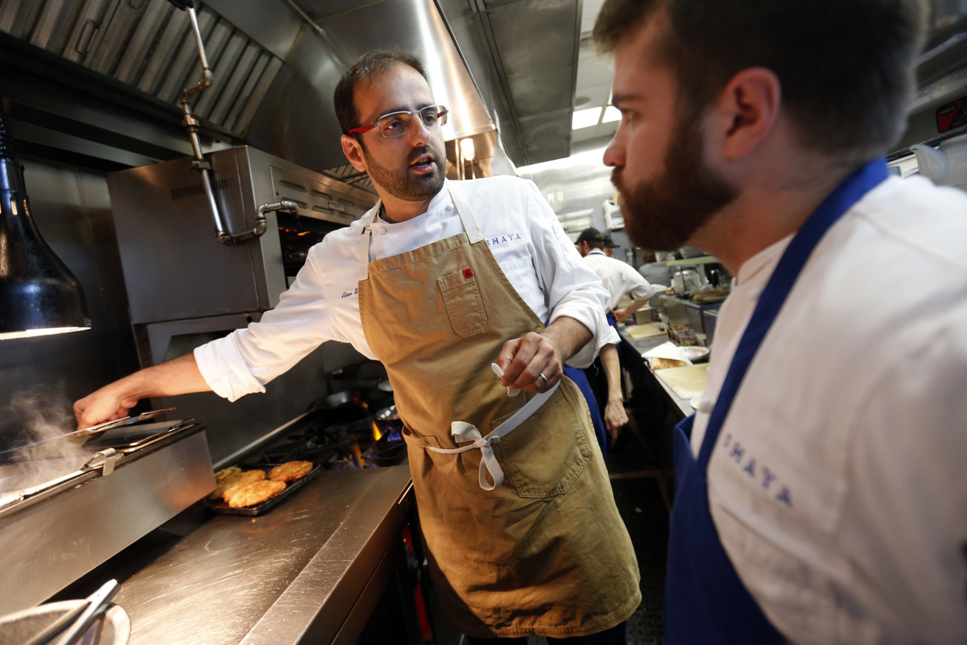 In this May 31, 2016 photo, Chef Alon Shaya, left, proprietor of Shaya Restaurant, works with sous chef Daniel Hollier at his restaurant in New Orleans. In 2015, Shaya opened his namesake restaurant, a bustling Israeli eatery on chic Magazine Street that the James Beard Foundation last month named the Best New Restaurant in the U.S. (AP Photo/Gerald Herbert)