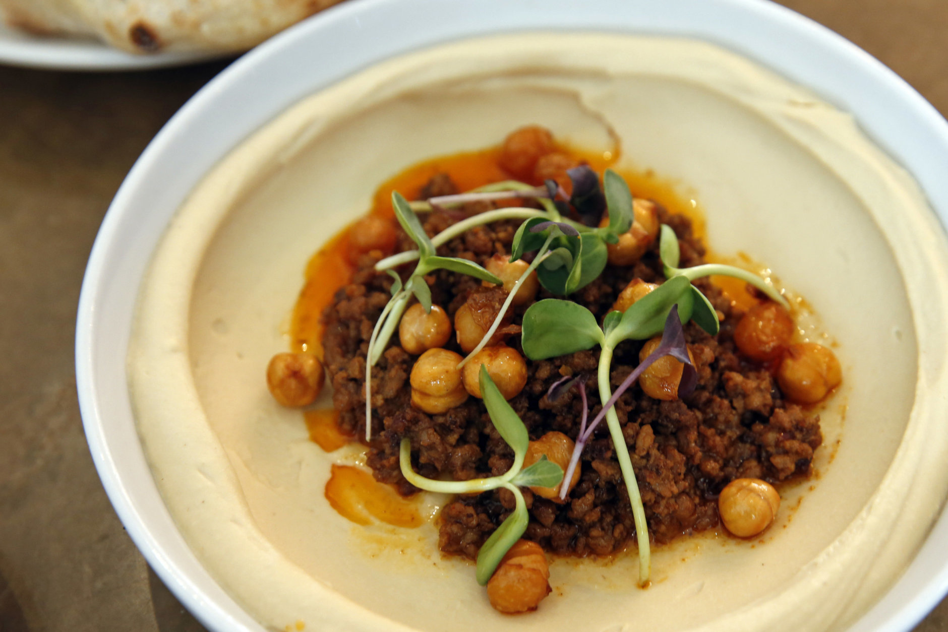 In this Tuesday, May 31, 2016 photo, lamb ragu hummus with crispy chickpeas, sits on a table at Shaya Restaurant, in New Orleans. In 2015, Shaya opened his namesake restaurant, a bustling Israeli eatery on chic Magazine Street that the James Beard Foundation in May named the Best New Restaurant in the U.S. In 2015, Shaya opened his namesake restaurant, a bustling Israeli eatery on chic Magazine Street that the James Beard Foundation in May named the Best New Restaurant in the U.S. (AP Photo/Gerald Herbert)