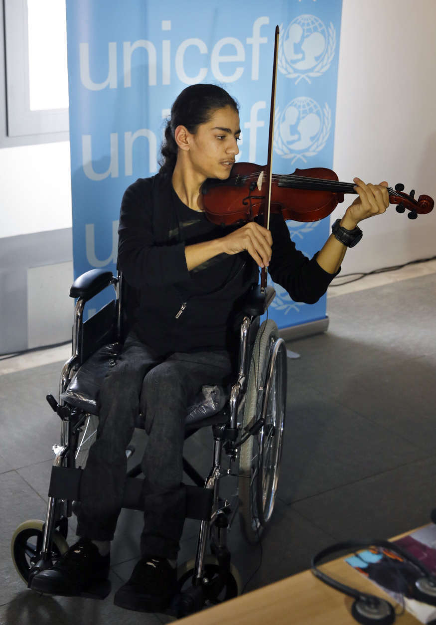 In this Monday, March 12, 2018 photo, Bassel Mokdad, 17, who is paralyzed from a spinal injury he incurred during the war in Syria, plays a violin during a press conference by UNICEF, in Beit Beirut museum and urban cultural center, Beirut, Lebanon. After seven years of war in Syria, the United Nations has one thing to say: Stop the war on children. Of Syria’s estimated 10 million children, 8.6 million are now in dire need of assistance, nearly 6 million children are displaced or living as refugees and about 2.5 million are out of school. (AP Photo/Bilal Hussein)