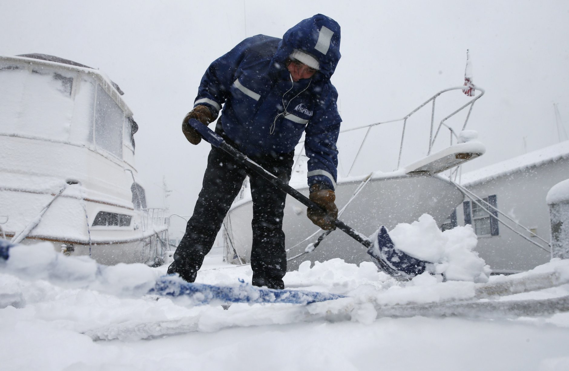 Gray Harrington clears snow from a dock at the Boston Harbor Shipyard and Marina in Boston, Tuesday, March 13, 2018. Boston finds itself in the bullseye of the third nor'easter in two weeks, with forecasters warning of up to 18 inches of snow and 2 feet or more to the south. (AP Photo/Michael Dwyer)