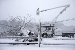 Workers remove a fallen tree from a road and repair power lines during a winter storm, Tuesday, March 13, 2018 in Norwell, Mass. The nor'easter is expected to deliver up to 2 feet of snow to some areas of New England. (AP Photo/Steven Senne)