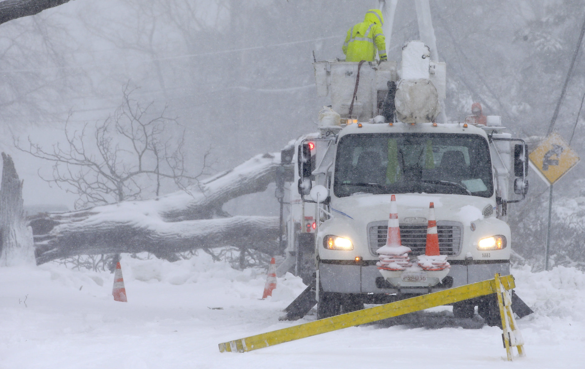Workers remove a fallen tree from a road and repair power lines during a winter storm, Tuesday, March 13, 2018, in Norwell, Mass. The nor'easter is expected to deliver up to 2 feet of snow to some areas of New England. (AP Photo/Steven Senne)