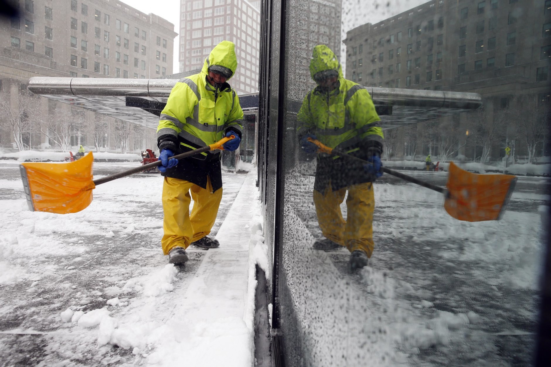 A worker shoveling snow is reflected in a building's plate glass window during a snowstorm, Tuesday, March 13, 2018, in Boston. (AP Photo/Michael Dwyer)