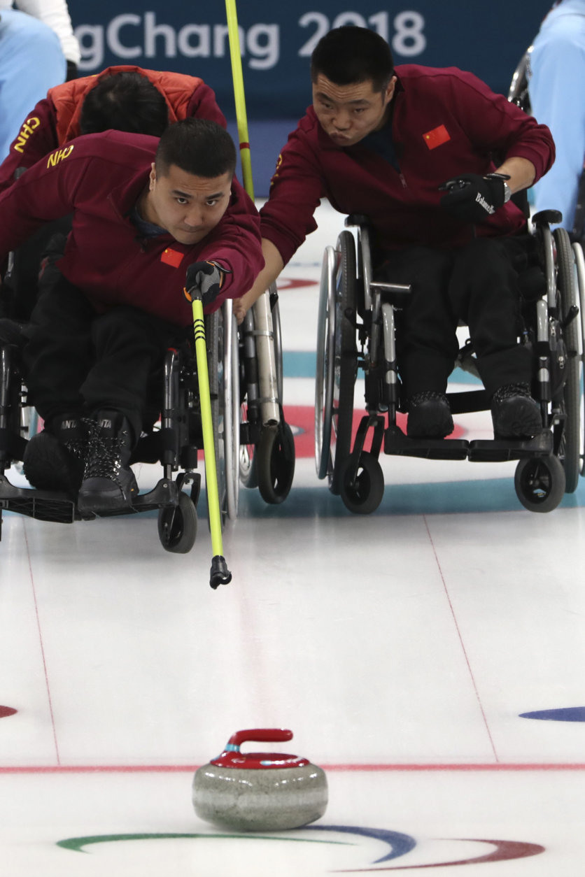 China's Wang Haitao throws a stone as teammate Liu Wei holds his Wheelchair steady during a Wheelchair Curling gold medal match against Norway for the 2018 Winter Paralympics at the Gangneung Curling Centre in Gangneung, South Korea, Saturday, March 17, 2018.(AP Photo/Ng Han Guan)