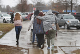 Parents walks their children, students from Great Mills High School, after picking them up from Leonardtown High School in Leonardtown, Md., Tuesday, March 20, 2018.   A teenager wounded a girl and a boy inside his Maryland high school Tuesday before a school resource officer was able to intervene, and each of them fired one more round as the shooter was fatally wounded, a sheriff said. St. Mary's County Sheriff Tim Cameron said the student with the handgun was declared dead at a hospital, and the other two students were in critical condition. (AP Photo/Carolyn Kaster)