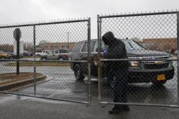 A man checks a locked gate to the parking lot of Great Mills High School, the scene of a shooting, Tuesday, March 20, 2018, in Great Mills. A student with a handgun shot two classmates inside the school before he was fatally wounded during a confrontation with a school resource officer, a sheriff said.  (AP Photo/Alex Brandon)