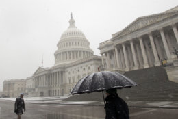Pedestrians walk under a snow fall outside of U.S. Capitol building, Wednesday, March 21, 2018, in Washington.The storm shut down federal offices in the D.C. area, closed schools and stopped two major commuter rail systems from operating. (AP Photo/Jose Luis Magana)