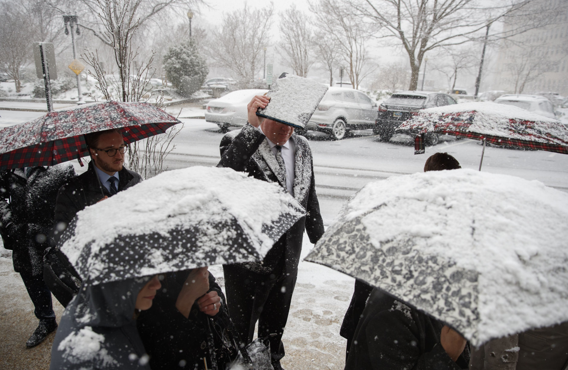 Ben Stein from Brandon, Miss., uses a folder to shield his head from falling snow as he waits in line to go through security to enter Dirksen Senate Office Building on Capitol Hill in Washington, Wednesday, March 21, 2018. The coming spring nor'easter caused the federal government to close its offices in the Washington area. (AP Photo/Carolyn Kaster)
