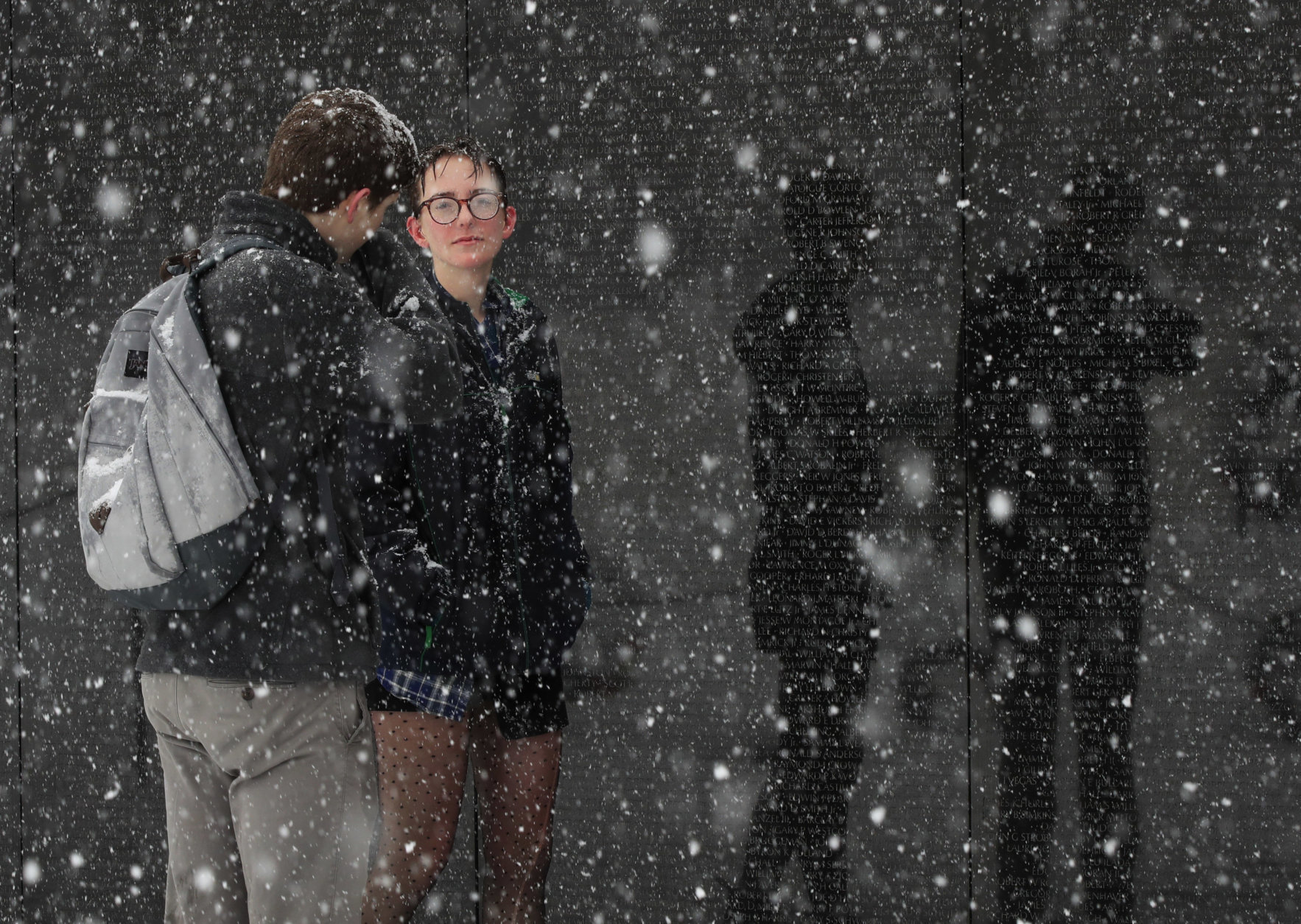 Washington visitor Haley Rich and Eric Merritt from Las Vegas, Nev., pause at the Vietnam Veterans Memorial on the National Mall in Washington during a Spring snow storm, Wednesday, March 21, 2018. The coming spring nor'easter caused the federal government to close its offices in the Washington area. (AP Photo/Manuel Balce Ceneta)