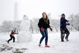 Dane Lariscy, 5, left, works on a snowman as his siblings, Amanda Lariscy, 17, and Blaze Lariscy, 15, laugh while having a snowball fight on the National Mall during the Ochlockonee, Fla., family's first snowfall, Wednesday, March 21, 2018, during a spring snowstorm in Washington. Their parents decided to wait out the storm instead of trying to drive to Florida in the snow. (AP Photo/Jacquelyn Martin)