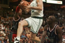 Boston Celtics forward Dino Radja, center, threads between Houston Rockets guard Clyde Drexler, right, and guard Sam Cassell while driving to the basket in the first half of NBA exhibition season action in Boston, Wednesday October 25, 1995. (AP Photo/Charles Krupa)