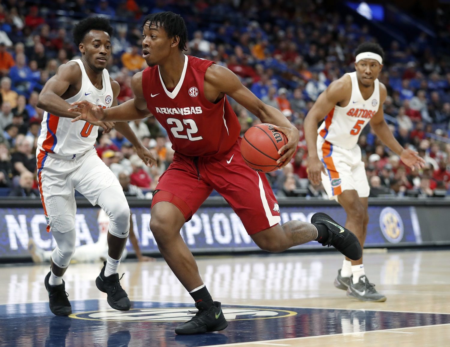 Arkansas' Gabe Osabuohien (22) heads to the basket as Florida's Mike Okauru, left, and KeVaughn Allen, right, defend during the first half of an NCAA college basketball game in the quarterfinals of the Southeastern Conference tournament Friday, March 9, 2018, in St. Louis. (AP Photo/Jeff Roberson)