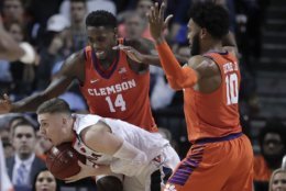 Virginia guard Kyle Guy (5) protects the ball from Clemson forward Elijah Thomas (14) and guard Gabe DeVoe (10) during the second half of an NCAA college basketball game in the Atlantic Coast Conference men's tournament semifinals Friday, March 9, 2018, in New York. (AP Photo/Julie Jacobson)