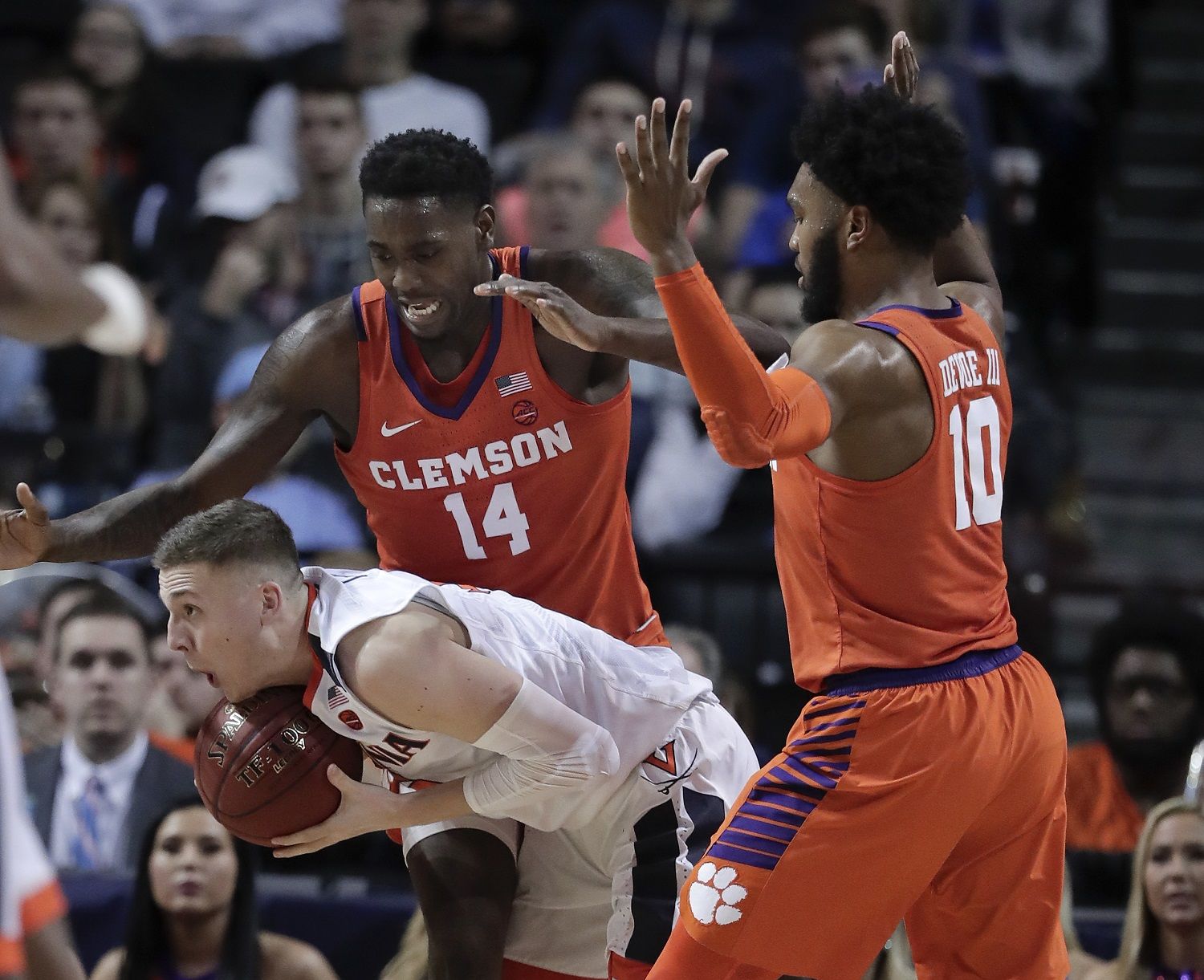 Virginia guard Kyle Guy (5) protects the ball from Clemson forward Elijah Thomas (14) and guard Gabe DeVoe (10) during the second half of an NCAA college basketball game in the Atlantic Coast Conference men's tournament semifinals Friday, March 9, 2018, in New York. (AP Photo/Julie Jacobson)