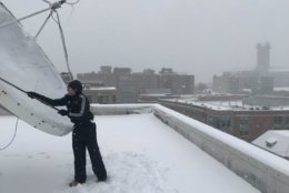 WTOP's Max Smith taking his turn to clear snow off the satellite dish atop the WTOP studio in NW. (WTOP/Chris Cichon)