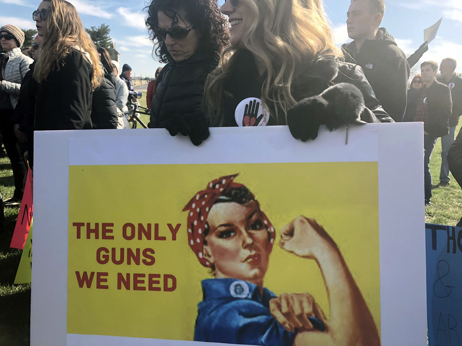A woman holds up a sign of Rosie the Riveter that says, "The only guns we need." (WTOP/Melissa Howell)