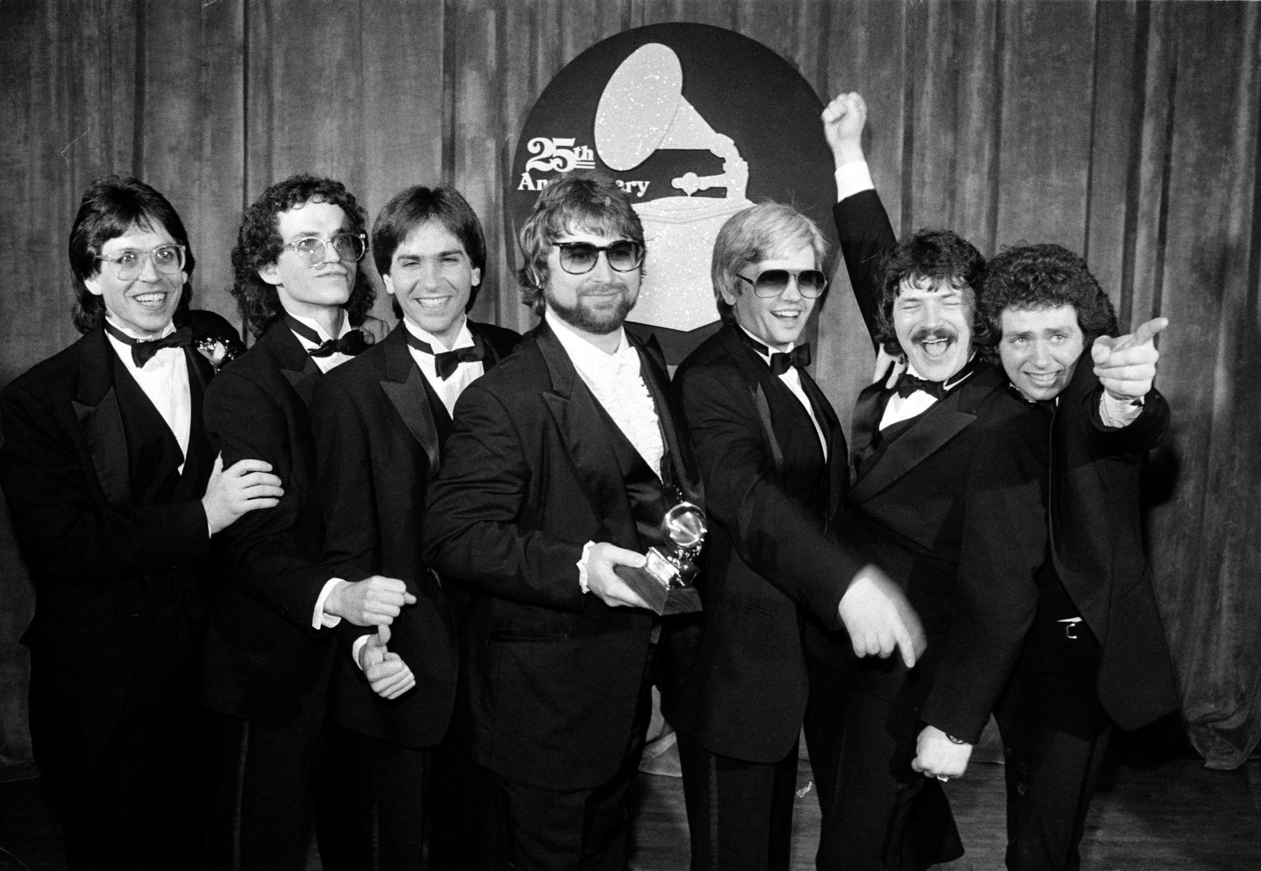 Band members of Toto pose after winning six Grammys during the 25th Annual Grammy Awards presentation in Los Angeles, Ca., Feb. 23, 1983.  Among the awards are record of the year for "Rosanna," album of the year for "Toto IV," and best instumental arrangement accompanying vocals for "Rosana."  From left are, Jeff Porcaro, Steve Porcaro, Michael Porcaro, Dave Paich, Dave Herngate, Bobby Kimball and Steve Lukather.  (AP Photo)