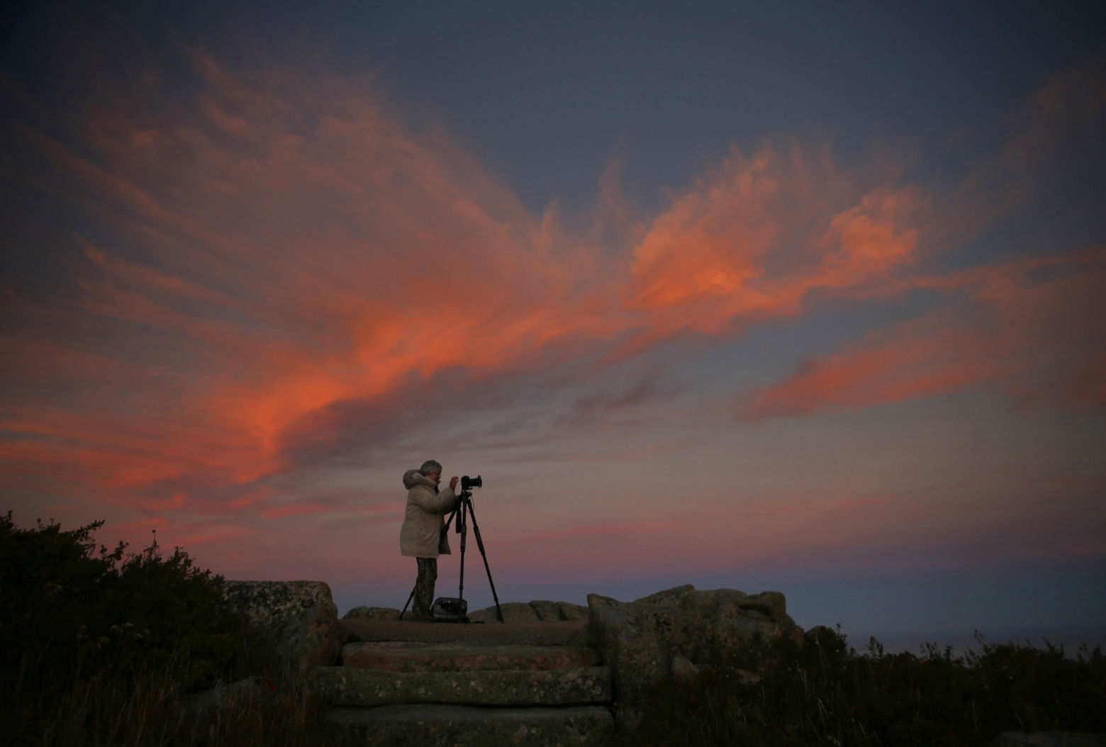Cindy Archbell photographs the landscape of Acadia National Park in Maine from the summit of Cadillac Mountain at sunset, Thursday, Oct. 2, 2014. Archbell, of Culpepper, Va., is spending a week in the park pursuing her photographic hobby.  "The first day I was here I spent 10 hours shooting," she said. (AP Photo/Robert F. Bukaty)
