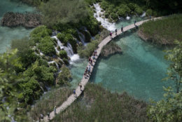 In this photo taken June 21, 2013, tourists walk across a bridge in the national park Plitvice, central Croatia. On Monday July 1, 2013, Croatia will become the 28th EU member, the bloc's first addition since Bulgaria and Romania joined in 2007. Croatia's membership marks a historic turning point for the small country, which went through carnage after declaring independence from the former Yugoslavia in 1991. (AP Photo/Darko Bandic)