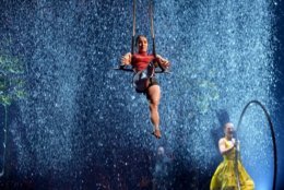An acrobat performs her routine with an onstage rainstorm as a backdrop.