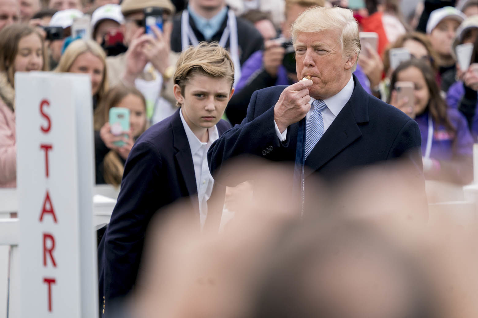 President Donald Trump, accompanied by his son Barron Trump, left, blows a whistle to start a race at the annual White House Easter Egg Roll on the South Lawn of the White House in Washington, Monday, April 2, 2018. (AP Photo/Andrew Harnik)