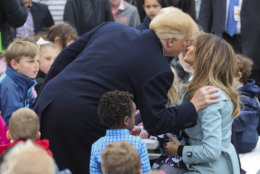 President Donald Trump leans over to kiss first lady Melania Trump, right seated, during the annual White House Easter Egg Roll on the South Lawn of the White House in Washington, Monday, April 2, 2018. (AP Photo/Pablo Martinez Monsivais)
