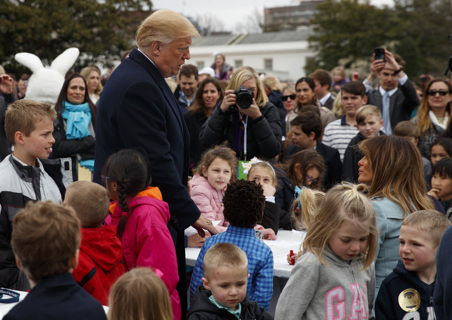 President Donald Trump talks with first lady Melania Trump as she sits at a table with children writing cards for troops at the White House in Washington, Monday, April 2, 2018, during the annual White House Easter Egg Roll. (AP Photo/Carolyn Kaster)