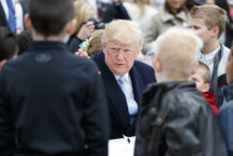 President Donald Trump sits with children writing cards for troops at the White House in Washington, Monday, April 2, 2018, during the annual White House Easter Egg Roll. (AP Photo/Carolyn Kaster)