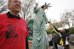Debbie Davis, of Milwaukee, Wisc., dressed on stilts as "lady liberty," gets a high five from Trinity Mitchell, 8, of Canton, Ohio, as they attend the A.C.T. To End Racism rally, Wednesday, April 4, 2018, on the National Mall in Washington, on the 50th anniversary of Martin Luther King Jr.'s assassination. At left is Art Laffin, of Washington. (AP Photo/Jacquelyn Martin)