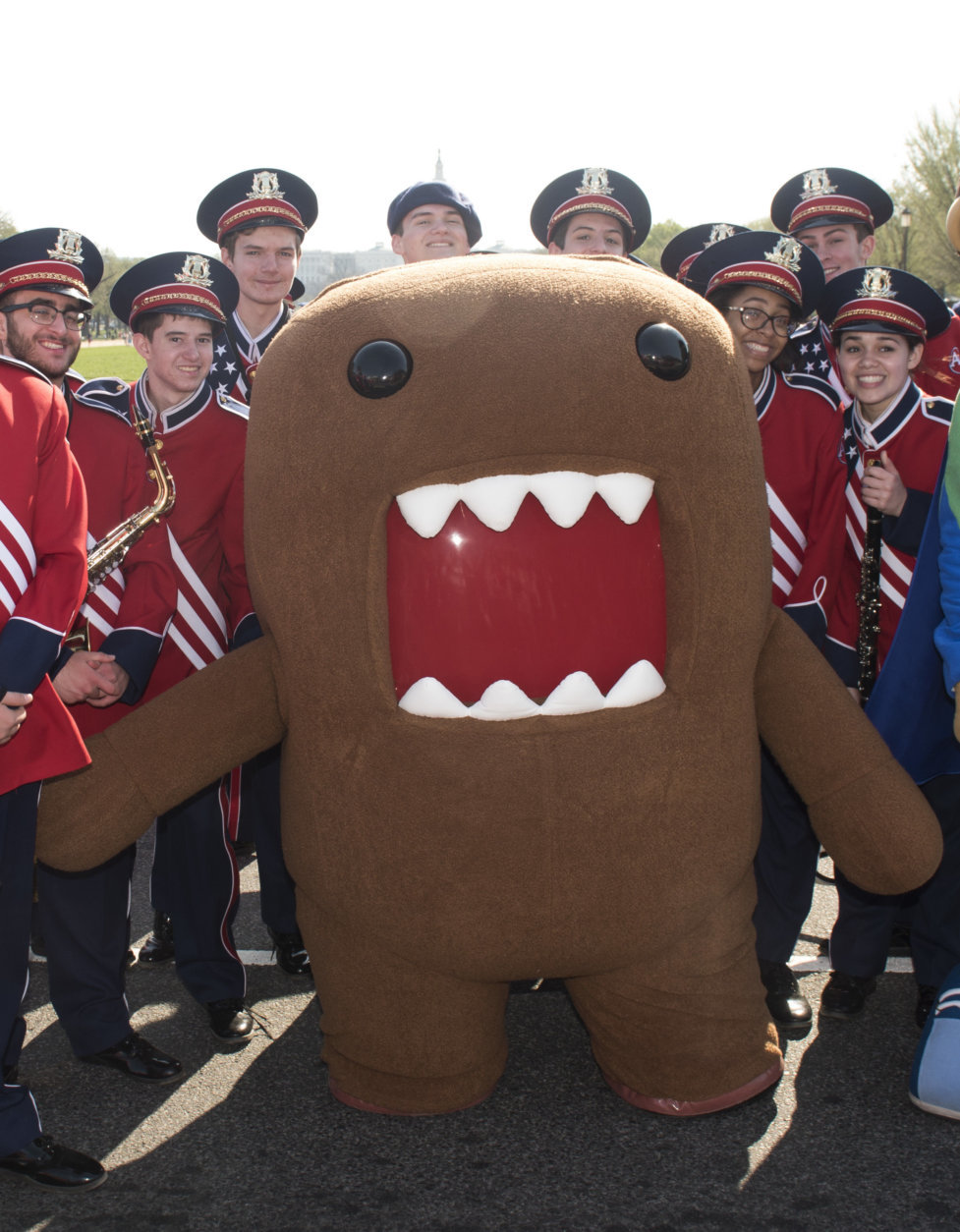 IMAGE DISTRIBUTED NHK WORLD - NHK WORLD-JAPAN's mascot, Domo, poses for a photo with members of the Austintown-Fitch High School marching band, from Austintown, Ohio, at the National Cherry Blossom Festival Parade on Saturday, April 14, 2018 in Washington. (Kevin Wolf/AP Images for NHK World)