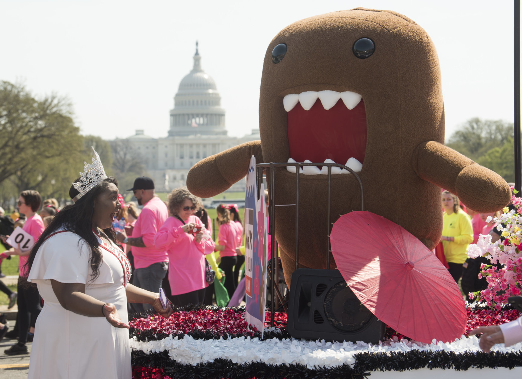 IMAGE DISTRIBUTED NHK WORLD - Miss University of the District of Columbia Tajah Franklin reacts to seeing NHK WORLD-JAPAN's mascot, Domo, at the start of the National Cherry Blossom Festival Parade on Saturday, April 14, 2018 in Washington. (Kevin Wolf/AP Images for NHK World)