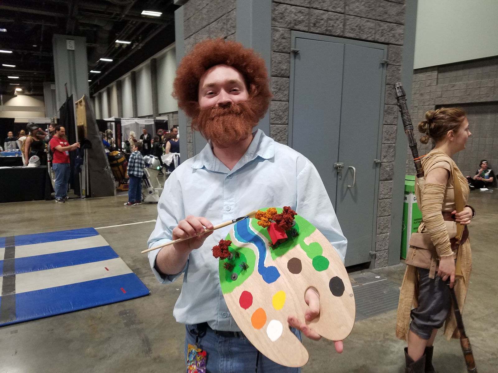 A man dressed as painter Bob Ross with several happy little trees on his palette. (WTOP/Will Vitka)