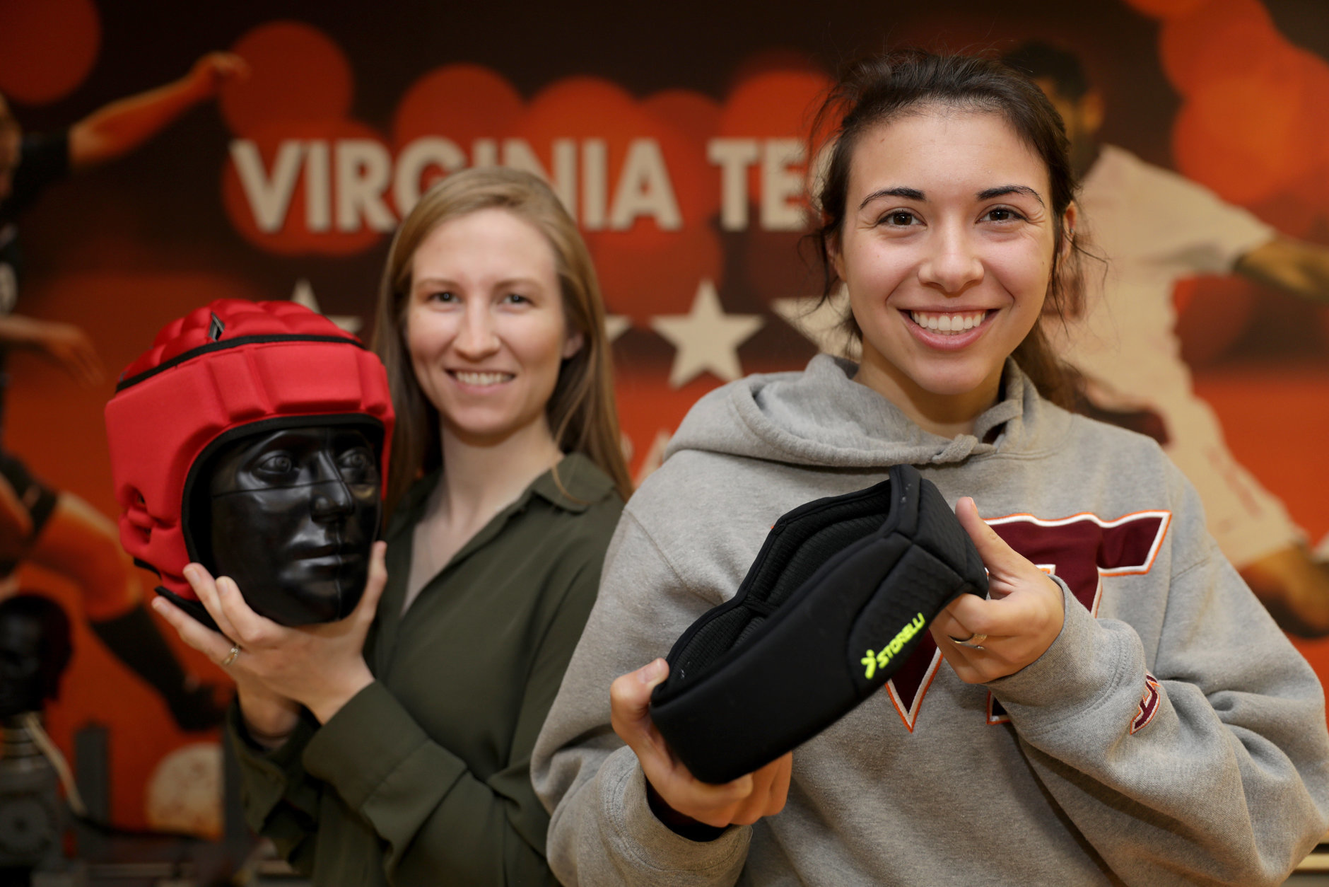 Abi Tyson, a Virginia Tech Helmet Lab research associate, and Megan Craig, a Helmet Lab intern, show off examples of protective soccer headgear. (Courtesy Virginia Tech)