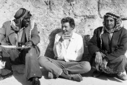 Peter O'Toole, center, the Irish actor who is to play the title role in the film "Lawrence of Arabia" squats on the dusty ground as he takes a glass of tea with a couple of Beduin farmers on April 20, 1961 in Amman, Jordan. O'Toole has spent several weeeks among the Jordanian Arabs learning their language, local customs and how to ride a camel. (AP Photo)