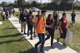David Hogg, left, a student activist from Marjory Stoneman Douglas High School speaks to a student as they walk out of their school, Friday, April 20, 2018 in Parkland, Fla.  Another wave of student walkouts is expected to disrupt classes Friday at hundreds of schools across the U.S. as young activists press for tougher gun laws. The protests were chosen to line up with the 19th anniversary of the Columbine High School shooting, which left 13 people dead in Littleton, Colorado. At 10 a.m., students plan to gather for moments of silence honoring the victims at Columbine and other shootings. (AP Photo/Terry Spencer)
