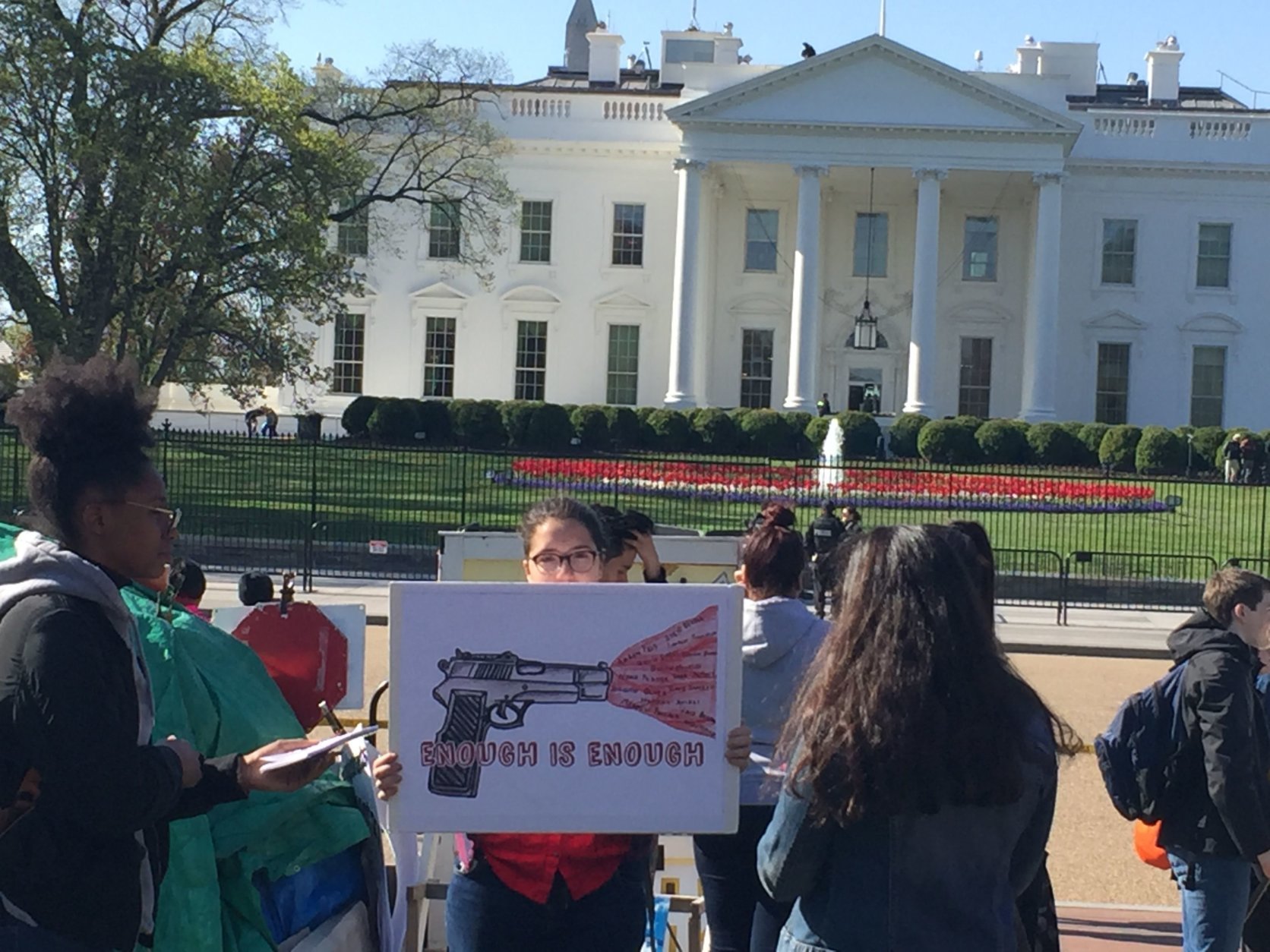 A student protester holds a sign that says, "Enough is enough" in front of the White House. (WTOP/John Domen) 