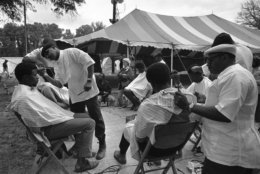 Five barbers go about their task, trimming the hair of some of the residents of Resurrection City in this open-air barber shop, May 20, 1968. (AP Photo/Bob Schutz)