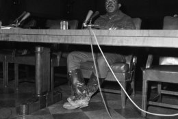 The Rev. Ralph Abernathy, head of the Southern Christian Leadership conference and leader of the Poor People's Campaign, displayed mud-caked boots as he testified in Washington on May 29, 1968 before a Senate subcommittee on manpower, poverty and employment. Before testifying, Abernathy had been at Resurrection City, which is covered with ankle deep mud after two days of rain. (AP Photo/Henry Griffin)