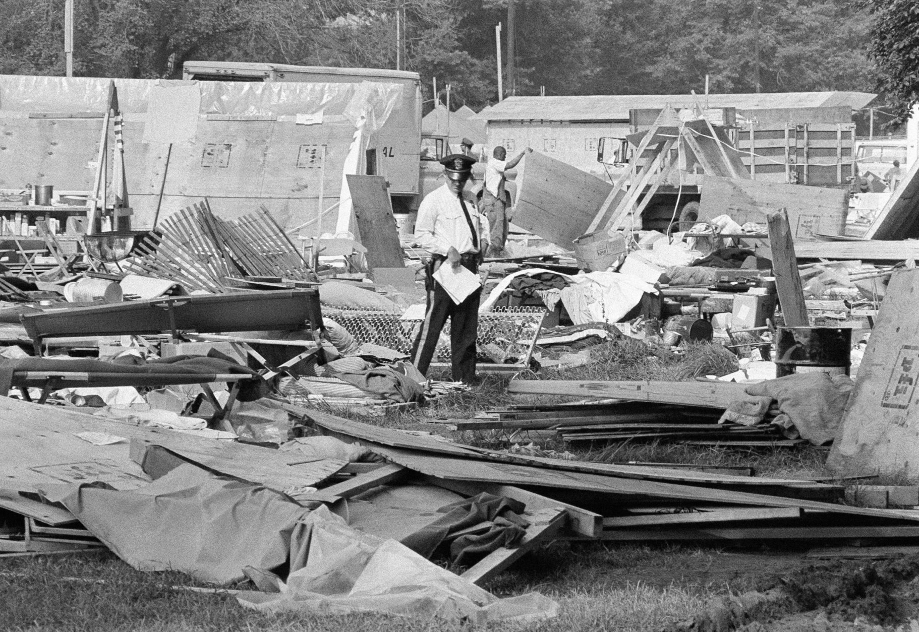 The possessions of former residents of Resurrection City are left on the flooring as the plywood and plastic shanties of the Poor Peoples Campaign are dismantled by workmen, June 25, 1968. Plywood sections are being loaded on trucks to be carted away. The possessions will be cataloged by tent and stored. (AP Photo/Bob Daugherty)