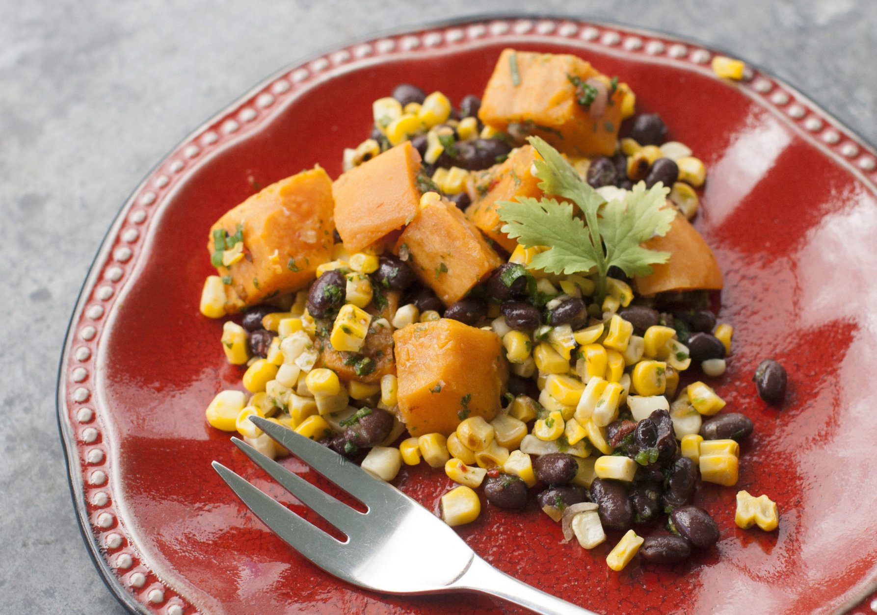 This May 5, 2014, photo shows sweet potato, grilled corn and black bean salad with spicy cilantro dressing in Concord, N.H. This recipe swaps sweet potatoes for the more traditional white potatoes and loses the standard recipes abundant mayonnaise in favor of a dressing high in flavor and low in fat. (AP Photo/Matthew Mead)