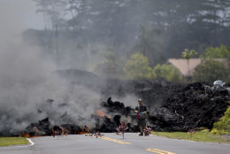 A man films the lava in the Leilani Estates subdivision, Saturday, May 5, 2018, in Pahoa, Hawaii. Hundreds of people on the Big Island of Hawaii are hunkering down for what could be weeks or months of upheaval as the dangers from an erupting Kilauea volcano grow. (AP Photo/Marco Garcia)