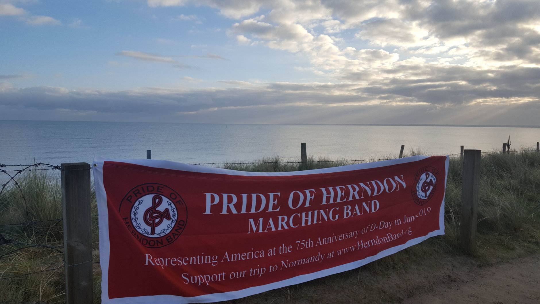 In anticipation of the June 2019 performance in France, band mom Margaret Jamborsky brought the band's banner to Utah Beach, the site of the U.S. Navy Memorial, dedicated to the more than 1,000 sailors who died there. 

"The USS Herndon would have been right in the center of the picture on D-Day," Jamborsky said. "It was quite moving to see such a beautiful, serene place, a far cry from what it would have looked like that day in 1944." (Courtesy Margaret Jamborsky)