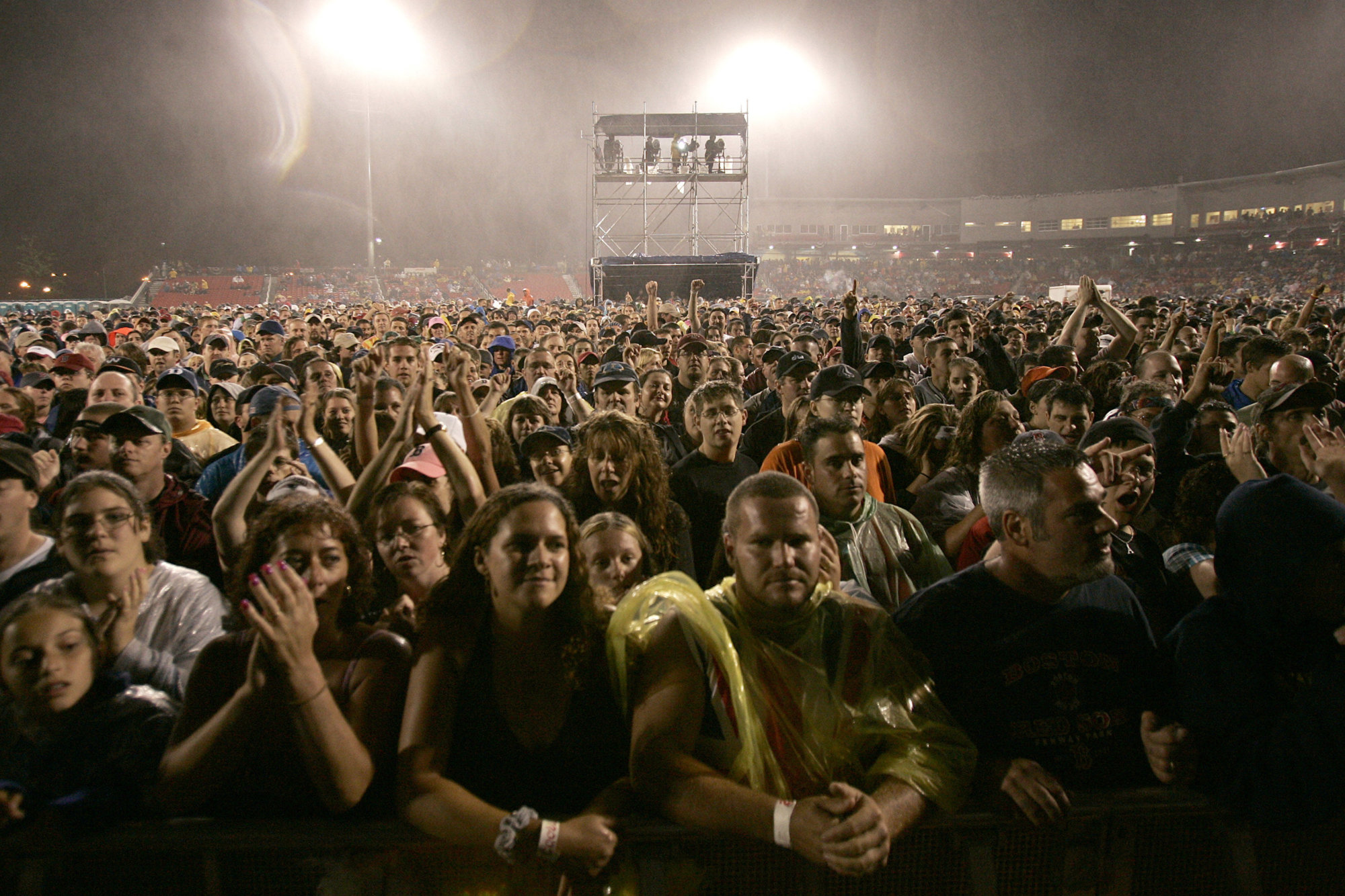 Rain-soaked fans watch British rock band Def Leppard perform at Campanelli Stadium in Brockton, Mass., July 6, 2005, during their summer tour with rock singer Bryan Adams. (AP Photo/Robert E. Klein)