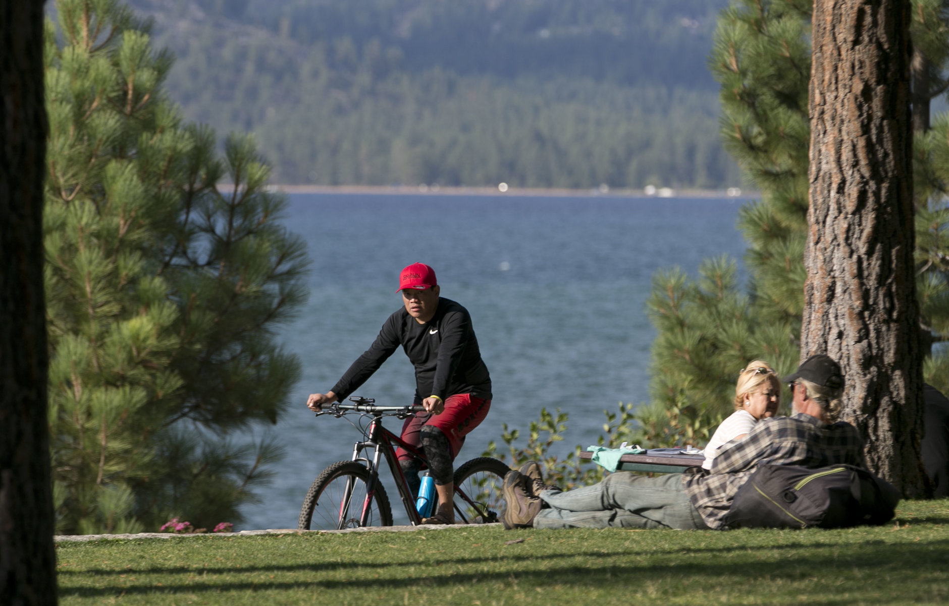 In this photo taken Tuesday, Aug. 8, 2017, a bicyclist rides down a path along the south shore of Lake Tahoe, in South Lake Tahoe Calif. (AP Photo/Rich Pedroncelli)