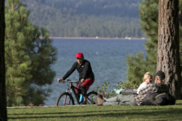 In this photo taken Tuesday, Aug. 8, 2017, a bicyclist rides down a path along the south shore of Lake Tahoe, in South Lake Tahoe Calif. (AP Photo/Rich Pedroncelli)