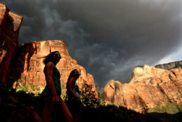 FILE - In this Monday, July 22, 2013, file photo, hikers look up at a fast moving storm as it makes its way through Zion National Park outside of Springdale, Utah. Both Zion and Bryce were formed millions of years ago when the Earth's crust violently heaved, leaving behind stunning, unique arrays of rock formations. (AP Photo/Sandy Huffaker, File)